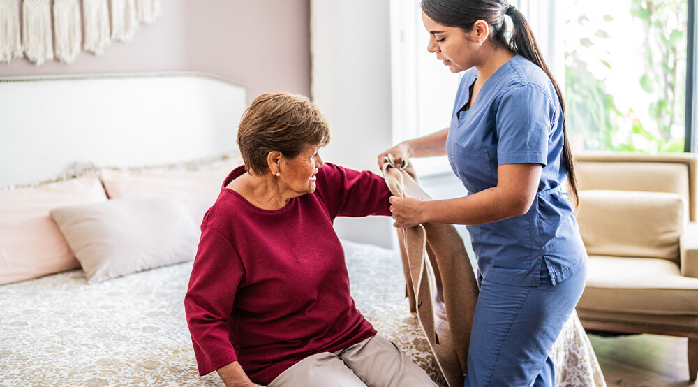caregiver helping a senior woman to get dressed